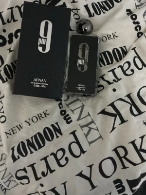 Afnan 9PM Eau de Parfum 100ml - Afnan 9PM Eau de Parfum är en elegant parfym i en stilren, rektangulär glasflaska med svart etikett och silverfärgad rund kork. Flaskan rymmer 100 ml och har en modern design som känns lyxig och trendig. Perfekt för dig som gillar unika dofter och snygga flaskor.