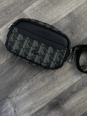 Lacoste Axelväska - Säljer nu denna underbara väskan. Aldrig använd utan är i nyskick, vid frågor är det bara att skriva.