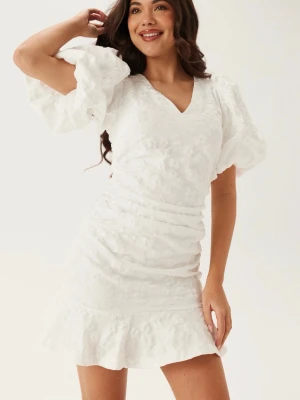 Vit kortklänning med puffärmar - Snygg vit kortklänning med v-ringning och puffiga kortärmar. Perfekt som studentklänning men var tyvärr inte min typ av klänning! Helt oanvänd med prislapp kvar!