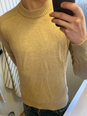 Beige stickad tröja från Selected Homme - Säljer en stilren beige stickad tröja från Selected Homme. Tröjan har rund halsringning och ribbade muddar vid ärmslut och nederkant. Perfekt för lager på lager och enkel att matcha med jeans eller chinos.