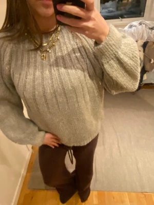 Ljusgrå stickad tröja  - Mysig ljusgrå stickad tröja med breda ribbor och ballongärmar. Tröjan har rund halsringning och ribbstickade muddar vid ärmslut och nederkant. Perfekt för lager på lager och en avslappnad look. Står storlek M/L men den passar absolut XS-L! ALDRIG ANVÄND!