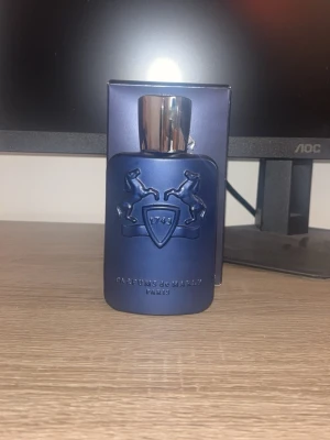 Parfums de Marly Layton EdP 125ml - Exklusiv parfym från Parfums de Marly, Layton Eau de Parfum i en elegant matt mörkblå flaska med silverfärgat lock. Flaskan har ett stilrent reliefmönster med två hästar och texten '1743'. Förpackningen matchar flaskans lyxiga känsla.