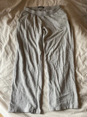Grå mjukisbyxor med resårmidja - Säljer ett par grå lågmidjade mjukisbyxor med rak passform. De är tillverkade i mjukt och stretchigt bomullsmaterial. Har använt dessa väldig få gånger då de krympte i tvätten och för mig (169cm) blev för korta. Inget fel alls på dem! 😌