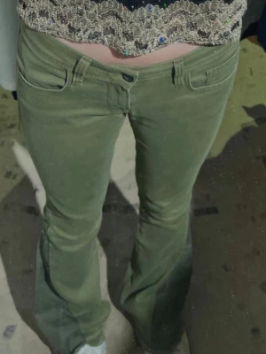 Olivgröna bootcut jeans - Säljer ett par lågmidjade olivgröna jeans i två toner som jag har sytt om själv med symaskin till bootcut. Se bild för inte helt perfekt men har sett till att de inte fransar sig. Har även sytt en söm längst ner för att de inte ska fransa sig. Från märket Mavi. Passar storlek 26-28 i waist och 32 i längd. Stretchigt material