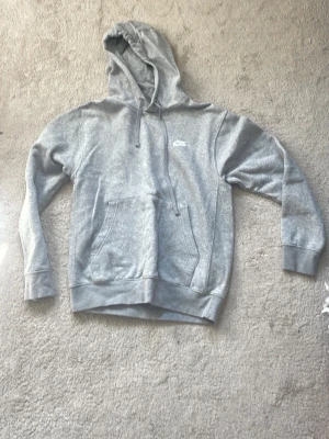 Nike hoodie - Säljer en grå Nike Hoodie. Den är ganska bra skick den har lite knottror på sig men det kan man få bort. 