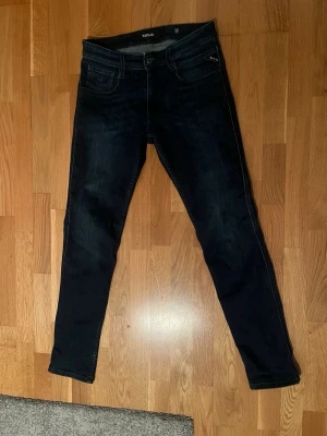 Mörkblå jeans från Replay - Säljer ett par mörkblå jeans från Replay med klassisk femficksmodell och dragkedja. Jeansen har smal passform och är tillverkade i denimtyg för extra komfort. Snygga detaljer och diskreta sömmar gör dem perfekta till din vardagsstil.