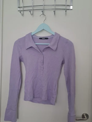 Ljuslila långärmad tröja - Ljuslila långärmad tröja från Bik Bok med krage och knappar framtill. Väldigt mjuk och med knappar fram som kan knäppas eller ha öppen. 