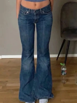 Levi's blå utsvängda jeans - Säljer ett par klassiska blå jeans från Levi's med utsvängda ben och hög midja. Jeansen har fem fickor, dragkedja och knapp framtill samt tydliga sömmar. Tillverkade i slitstark denim som ger en snygg vintagekänsla. Lånade bilder*