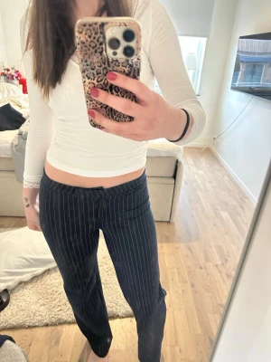 Mörkblå randiga kostymbyxor - Säljer ett par mörkblå kostymbyxor med smala vita kritstrecksränder. Byxorna har rak passform och låg midja. 💞