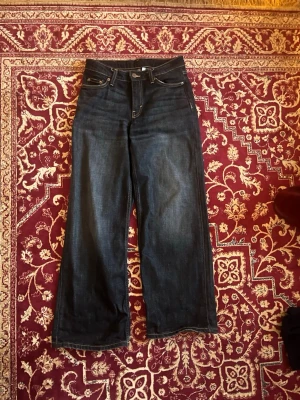 Mörkblå raka jeans från Weekday - Snygga mörkblå jeans från Weekday med raka ben och hög midja. Klassisk femficksmodell med kontrastsömmar och läderpatch bak i midjan. Jeansen är i kraftig denim och har en tidlös look som passar till det mesta. Str 24/30