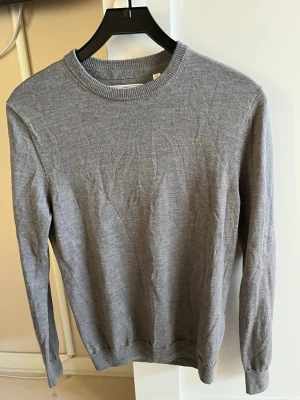 these glory days tröja - En stilren grå stickad tröja med rund hals och långa ärmar. Tröjan har ribbstickade muddar vid ärmslut och nederkant. Perfekt att matcha med jeans eller kjol för en enkel och snygg look.