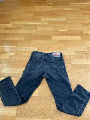 Svarta jeans från Diesel  - Säljer ett par svarta jeans från Diesel med raka ben och klassiska bakfickor. Jeansen har en snygg tvättad look och detaljerade sömmar. Perfekta för dig som gillar en avslappnad stil. Materialet är bomullsdenim.