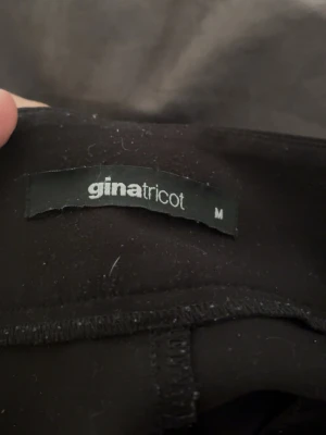 Svarta kostymbyxor Gina Tricot M - Säljer ett par svarta kostymbyxor från Gina Tricot i storlek M. Byxorna har klassisk rak passform med knapp och dragkedja framtill. Perfekta för dig som vill ha en stilren och enkel look. Materialet känns mjukt och följsamt.