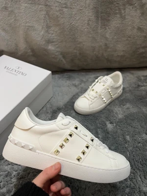 Valentino Rockstud/ Opens - vit/guldiga - Tjena! Säljer nu dessa valentino rockstuds. Helt nya, aldrig använda. Skicket är 10/10. De är vita med guldiga spikar. Storlek 38, passar 37/39. Så fråga gärna. Priset går att diskretas vid snabbaffär 