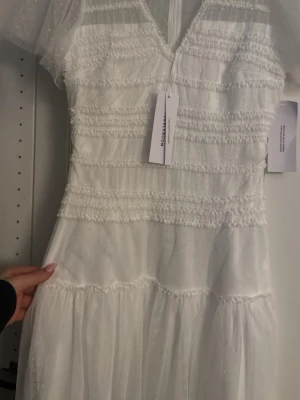 Vit romantisk klänning från Bubbleroom  - Superfin vit klänning från Bubbleroom som nu är slutsåld. Klänning har v-ringning, transparenta korta ärmar i mesh och volangdetaljer. Klänningen har dragkedja i ryggen och är dekorerad med små prickar i tyget. Perfekt för sommarens alla tillfällen men speciellt till studenten! 
