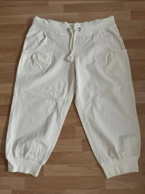 Nya. Vita sommar Capri byxor med dragsko - Säljer ett par vita Capri byxor med dragsko i midjan och breda muddar vid bensluten. Byxorna har två fickor fram och en bakficka. Sköna och avslappnade, perfekta för chill dagar. Tillverkade i mjukt bomullsmaterial. 