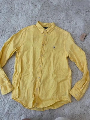 Gul linneskjorta från Polo Ralph Lauren - Tjena, säljer denna gula linneskjorta från Ralph Lauren. Riktigt schysst till sommaren och varma kvällar! Barnstorlek XL vilket passar som herr S. Kontakta vid funderingar!