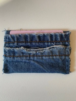 Handgjord jeans plånbok - Unik plånbok sydd av återvunnet blått denimtyg med råa kanter och slitna detaljer. Plånboken har flera kortfack och en cool, avslappnad look. Perfekt för dig som gillar streetstyle och vill ha något annorlunda. Plånboken är gjord av vårat uf företag deni_mdesign