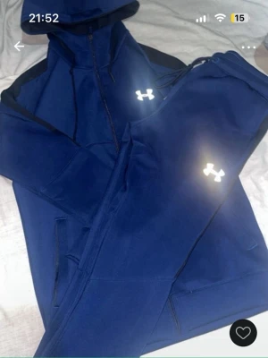 Blå Under Armour set  - Säljer ett blått loungewear set från Under Armour med matchande hoodie och byxor. Setet har dragkedja på tröjan, huva och resår i midjan på byxorna. Båda delarna har Under Armour-logga framtill. Perfekt för chill dagar hemma. Storlek M. Snörena på både tröjan och byxorna saknas!