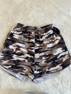 Camo shorts med elastisk midja SHEIN 150  - Snygga shorts med camouflage-mönster i bruna, beige och svarta toner. De har elastisk midja och är tillverkade i ett mjukt och lätt material, perfekt för varma dagar. Passar dig som gillar streetstyle och vill sticka ut lite extra. Pris kan diskuteras 