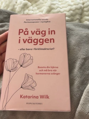 Bok - På väg in i väggen  - En rosa bok med titeln 'På väg in i väggen' av Katarina Wilk. Boken handlar om förklimakteriet, hormoner och hur man boostar hjärnan och mår bättre när hormonerna svänger. Helt ny aldrig ens läst, men litet märke ifram som syns på bilden.