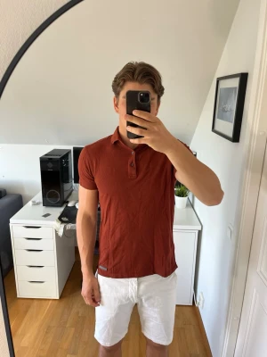 Rödvin piketröja från Massimo dutti - Snygg vinröd pikétröja från Massimo dutti med klassisk krage och två knappar framtill. Tröjan har korta ärmar och en slim passform som sitter snyggt på kroppen. Det följer med 1 extra knapp. Hör gärna av dig vid frågor!