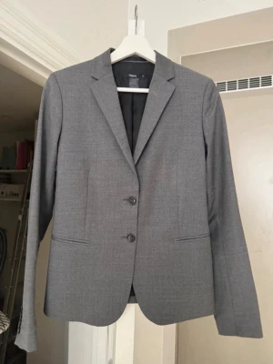 Filippa K - kavaj  - Stilren kvalitetskavaj från Filippa K. Kavajen har raka linjer, två fickor och är helfodrad. Släng den över axlarna och din sommarklänning eller för en clean och snygg look till vardags, till jeansen och den vita T-shirten. Materialet är tunna, slätt och känns bekvämt.