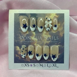 MidnightStar (S);Medium Almond - Snygga handgjorda press-on naglar i en medium lång mandelform med vit fransk tipp och blå stjärnor. En nagel har en dekorativ rosett i 3D. Naglarna har en naturlig nude bas och kommer i flera storlekar. Perfekt för dig som vill ha en unik och trendig look.