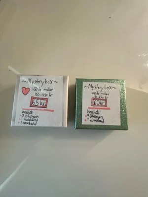 Mysterybox med smycken - Mysterybox med blandade smycken: 3 par örhängen, 1 halsband och 1 armband. Boxarna är i olika färger, en vit och en grön, och innehållet är en överraskning. Perfekt för dig som gillar att testa nya accessoarer och vill ha något unikt. Ena kostar 60 och andra kostar 65 kronor.