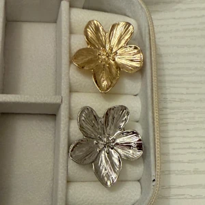 ‼️Massa nya ringar i lager! ‼️ - Två stora ringar i form av blommor, en i guld och en i silverfärg. Båda har detaljerade blomblad med en glansig finish som ger ett lyxigt intryck. Perfekta för dig som vill sticka ut med ett unikt smycke. ( Styck pris )