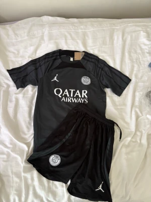Svart PSG fotbollskit Jordan - Brasilien fotbollsträningsset i storlek S. Shortsen har fickor med dragkedjor. Helt nya och oanvända, perfekt till sommaren. Hör gärna av vid frågor!