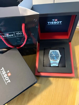 Tissot PRX Quartz 35mm – Mycket fint skick – Komplett med box & påse - Säljer min Tissot PRX Quartz 35 mm med blå urtavla i mycket fint skick.  Klockan är väl omhändertagen och fungerar perfekt. Glaset är helt fritt från repor, och klockan är överlag i mycket fint kosmetiskt skick.  Det som ingår:  * Original Tissot-box * Original Tissot-påse * Klockan  Kvitto finns tyvärr inte, vilket är anledningen till att priset är anpassat därefter.