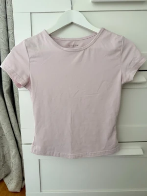 Ljusrosa kortärmad t-shirt från SHEIN - En enkel och stilren ljusrosa t-shirt från SHEIN. Modellen är kortärmad med rund halsringning och har en normal passform. Perfekt att matcha med jeans eller kjol för en clean look.