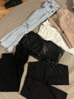 Jeans och byxor i olika färger - Blåa jeans  ”Queen hearts” strl S (passar xs/34) 20kr. Vita jeans slim ”lager 157” strl L (passar M) 10kr.  Skinnbyxor raka ”Bikbok” strl 36 as snygga 100kr. Kostymbyxor beige fås vid köp då de uppsprättade i bak syns knappt ( se bild) svarta kostymbyxor ish utsvängda strl kort s 20kr. Shorts ”HM sport” 30kr. Knappt använda plagg, shorts helt oanvänd.  Paketpris 130kr