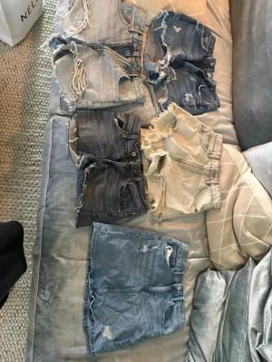 Fem par slitna jeansshorts - Säljer fyra par jeansshorts och en kjoli olika blå och beige nyanser. Alla har slitna detaljer och råa kanter för en avslappnad look. Perfekta för sommaren och passar till det mesta. Olika tvättar och längder, vissa med hög midja. Passar även storlek small