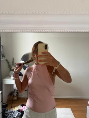Ljusrosa  topp - Säljer en ljusrosa  topp med hög hals och öppen rygg. Toppen är tight och har en stilren, modern look som passar perfekt till sommaren. Materialet känns mjukt och stretchigt, vilket gör den bekväm att bära hela dagen.