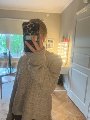 Beige oversized stickad tröja - Mysig beige stickad tröja med oversized passform och långa ärmar. Tröjan har en enkel design utan synliga loggor eller mönster och är perfekt för lager-på-lager. Materialet ser ut att vara mjukt och fluffigt, vilket gör den extra skön att bära.