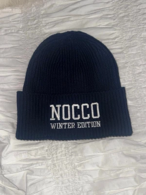 Marinblå NOCCO mössa Winter Edition - Säljer en limiterad mössa från NOCCO med vit brodyr där det står 'NOCCO WINTER EDITION' framtill. Använd nån enstaka gång