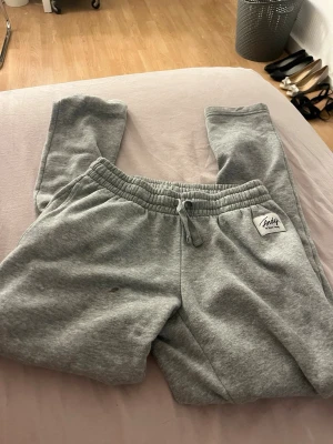 Grå mjukisbyxor Andy XS - Säljer ett par grå mjukisbyxor från Andy by Pink Daisy i storlek XS. Byxorna har resår och dragsko i midjan samt muddar vid bensluten. Tillverkade i mjukt och skönt material, perfekta för chill dagar hemma.