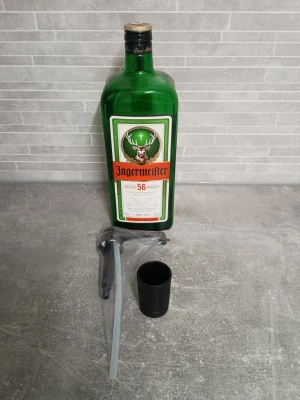 Jägermeister flaska med tillbehör - Grön glasflaska Jägermeister med klassisk etikett .Medföljer svart glasmugg och pump av plast. Perfekt för dig som gillar att blanda drinkar eller vill ha en snygg flaska till samlingen.