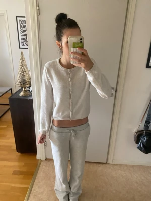 Vit stickad kofta med knappar - Snygg vit cropped kofta med rund halsringning och knäppning framtill. Koftan har långa ärmar och en enkel, stilren design som passar perfekt till jeans eller mjukisbyxor. Mjuk och skön kvalitet.