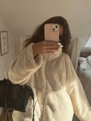 Beige oversized teddyjacka - Säljer en supermjuk och fluffig beige teddyjacka med hög krage och dragkedja framtill. Jackan har en oversized passform och långa ärmar, perfekt för att hålla värmen. Matcha med en cool väska för en trendig look. Köpt för 700-800.