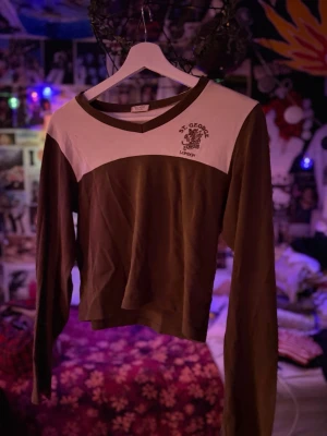 Brun och vit långärmad topp St. George - Säljer en brun och vit långärmad topp från St. George London. Toppen har v-ringning, tryckt logga på bröstet och är croppad i modellen. 