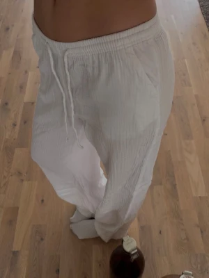 Vita linnebyxor med dragsko - Säljer ett par vita linnebyxor med avslappnad passform och resår i midjan samt dragsko. Byxorna har sidofickor och är gjorda i ett tunt, luftigt linnematerial som passar perfekt till sommaren. Använt en gång bara ! 