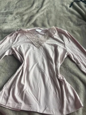 Ljusrosa långärmad topp med spets - Supersöt ljusrosa Intimissmi -topp från Gina Tricot med långa ärmar och v-ringning dekorerad med spetsdetaljer. Tillverkad i mjukt och stretchigt material som känns skönt mot huden. Perfekt för mysiga hemmakvällar.