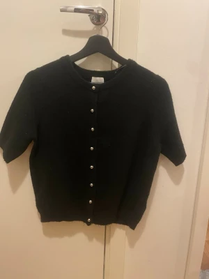 Svart kortärmad kofta med pärlknappar - Stickat material 