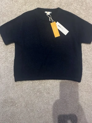 Mörkblå stickad kortärmad topp från gina tricot - En enkel och stilren mörkblå topp från gina tricot med korta ärmar och rund hals. Toppen har en loose passform och är tillverkad i mjukt material som passar perfekt till många olika outfits.
