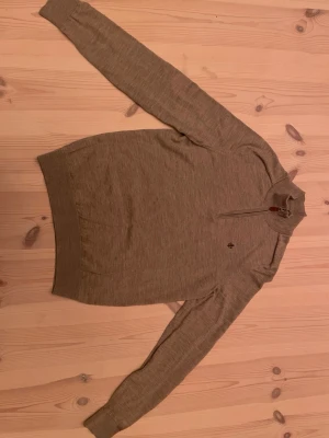 Beige stickad halvziptröja Morris  - Stickad 1/4 zip tröja i beige från Morris. 100% merino ull. Hör av er om ni har frågor
