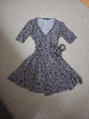 Ralph Lauren svartvit omlottklänning med knyt - Elegant mönstrad omlottklänning fran Ralph Lauren. Smickrande modell med V-ringning, knyt i midjan och fint fall i kjolen. Klassisk och tidlös design. Storlek: 8 (motsvarar ca M) Skick: Mycket fint skick Skriv gärna om du vill ha mått eller fler bilder. Skickar snabbt