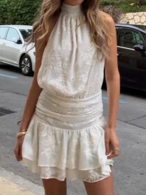 Vit studentklänning  - Supersöt vit mini klänning med halterneck, öppen rygg,  broderade blommor och volanglager. Perfekt nu till studenten!              Slutsåld och helt ny. Inte hunnit lämna tillbaka och har klänningen i både str 36 & str 38:) säljer även på vinted